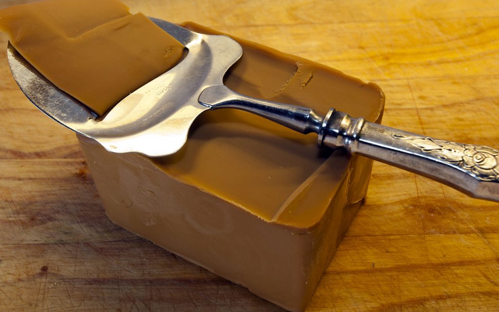Brown cheese with a silver cheese slicer